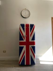 a clock on a wall with a flag on a couch at Casetta Beatrice Tivoli Holiday Home (British) in Tivoli