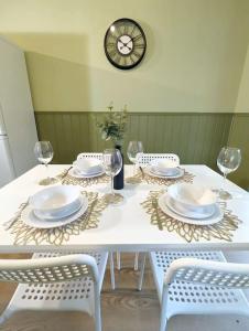a white table with chairs and plates and a clock at 3-Bed, Sleeps 6, 1 Bath, Parking, WiFi in Shalford +15 photos