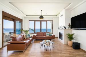 een woonkamer met een bank en een tv bij Beachfront Villa Atalandia with Heated Pool, Gym, BBQ & Office in Goúdhouros