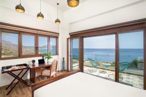 een slaapkamer met een bed en een bureau met uitzicht op de oceaan bij Beachfront Villa Atalandia with Heated Pool, Gym, BBQ & Office in Goúdhouros