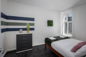 a bedroom with a bed and a dresser and a window at South Pier Apartments by Sasco in Blackpool