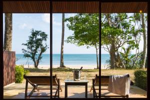 Zimmer mit Tisch und Stühlen und Strandblick in der Unterkunft Anda Lanta Resort in Ko Lanta