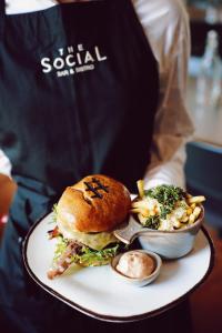 a person holding a plate with a sandwich and a bowl of food at Quality Hotel River Station in Drammen