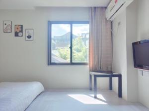 a bedroom with a bed and a tv and a window at Onederz Hostel Hangzhou in Hangzhou