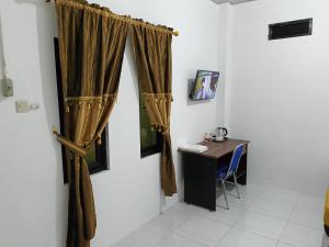 a room with a desk and a curtain on a wall at Solo Nadamax City Guest House Syariah in Bonorejo