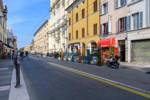 une rue urbaine vide avec des bâtiments et une moto garée dans la rue dans l'établissement Parma Parco Ducale Cozy Apartment, à Parme