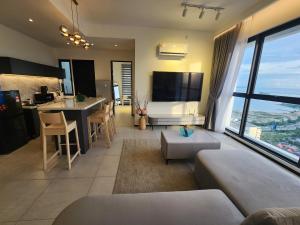 a living room with a couch and a kitchen with a large window at Urban Suite - George Town in Jelutong