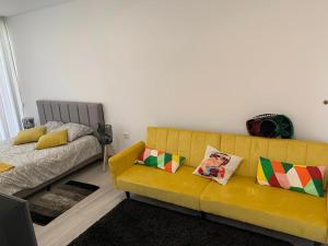 a living room with a yellow couch and a bed at Oliver Beach House in Poço da Cruz