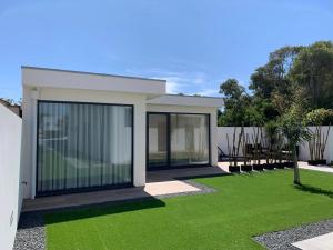 a house with a green lawn in front of it at Oliver Beach House in Poço da Cruz