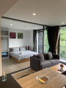 a bedroom with a bed and a couch and a table at The Valley at Sunshine, Panoramic in Pak Chong