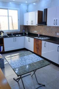 a kitchen with white cabinets and a table in it at séjournez auprès de toutes les commodités in Sousse