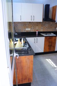 a kitchen with white cabinets and a black counter top at séjournez auprès de toutes les commodités in Sousse