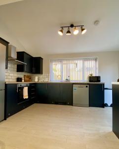an empty kitchen with black cabinets and appliances at Gable House in Crewe