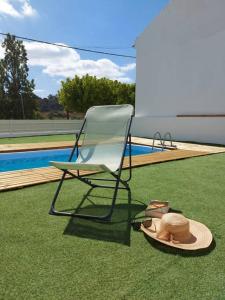 una silla y un sombrero en el césped cerca de una piscina en A Casa do Arez, en Alcácer do Sal