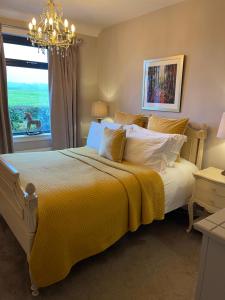 a bedroom with a bed with a yellow blanket and a window at Woodend Cottage in Dumfries