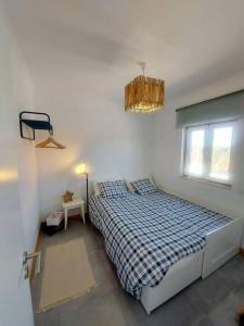 1 dormitorio con cama, ventana y lámpara de araña en A Casa do Arez, en Alcácer do Sal