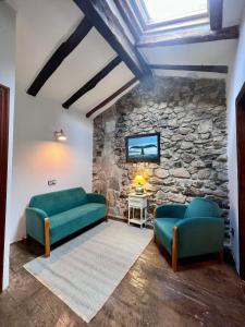 una sala de estar con 2 sofás verdes y una pared de piedra. en Casa Rural Basiver - Habitación Braña de Los Tejos, en Armaño