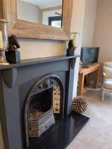 a living room with a fireplace with a mirror at Woodend Cottage in Dumfries