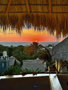 una sombrilla de paja con vistas a la puesta de sol en Villa Macarena Apartamentos Boutique - Adults Only en Puerto Escondido