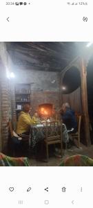 dos hombres sentados en una mesa frente a una chimenea en Cottage and Gigo Papa's Wine Cellar, en Kvareli
