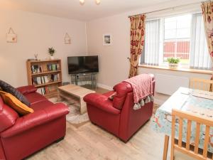 sala de estar con sofá rojo y TV en Goldfinch en Grindon