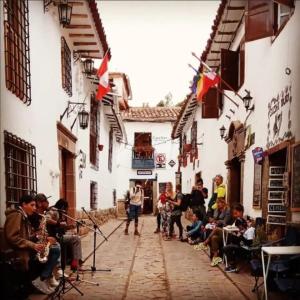 un grupo de personas de pie en una calle con instrumentos en Hostal Tunupa, en Cusco