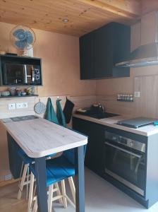a kitchen with a wooden table and blue chairs at Un petit coin de paradis in Orpierre
