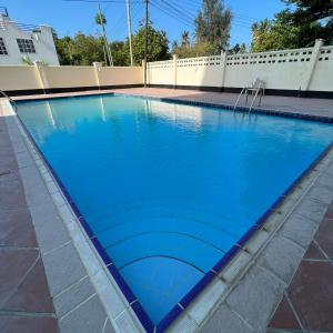 una piscina con acqua blu di fronte a una recinzione di En-Suite Rooms W/Pool & Gym in Mikocheni Near Beach a Dar es Salaam