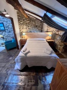 1 dormitorio con 1 cama grande y pared de piedra en Casa Rural Basiver - Habitación Braña de Los Tejos, en Armaño
