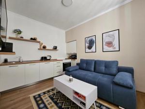 a living room with a blue couch and a kitchen at BLUE APARTMENT MOSTAR in Mostar