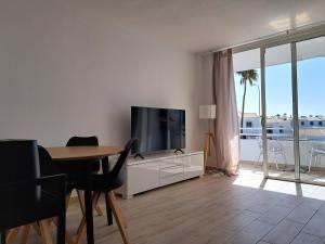 un soggiorno con TV e tavolo con sedie di Modern apartment with Pool in Golf del Sur a San Miguel de Abona