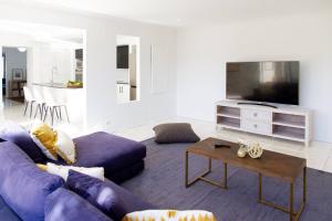 sala de estar con sofá púrpura y mesa en Sunny & Spacious Family Retreat, en Prestons