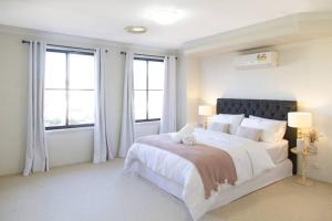 1 dormitorio blanco con 1 cama grande y ventanas en Sunny & Spacious Family Retreat, en Prestons