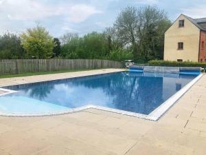 a swimming pool in a yard with a fence at Cosy Cotswold Cottage - Jacobs Cottage in Cirencester