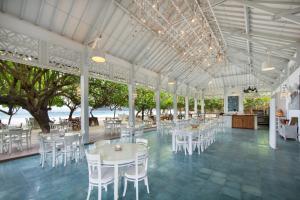 um salão de banquetes com mesas brancas e cadeiras brancas em Sempiak Seaside Resort em Selong Belanak