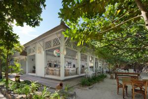 un bâtiment avec des tables, des chaises et des arbres dans l'établissement Sempiak Seaside Resort, à Selong Belanak