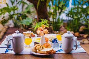 una mesa con una bandeja de alimentos para el desayuno y zumo de naranja en Armação dos Búzios Pousada Design, en Búzios