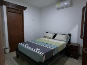 Cama pequeña en habitación con puerta de madera en Balcones de la Rivera Apartamento Azulejo 3, en Buga