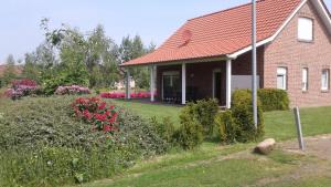 una casa de ladrillo con techo rojo y algunas flores en Haus Seeblick Nr 48, en Geeste