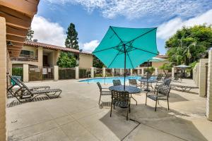 a patio with tables and chairs and a blue umbrella at San Diego Condo Pool Access, 8 Mi to Downtown in San Diego