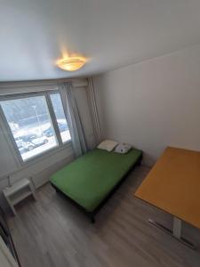 um pequeno quarto com uma cama verde e uma janela em Central Park Home em Turku