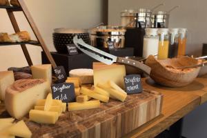 a bunch of cheese on a cutting board with a knife at Hotel Vincenz in Brigels