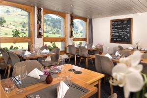 un ristorante con tavoli e sedie in legno e finestre di Hotel Vincenz a Brigels