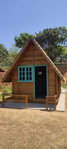 Cabaña de madera con puerta grande y banco en Chácara do sossego en Passa Quatro