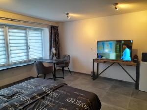 1 dormitorio con 1 cama, TV y mesa en Chez Francis en Verviers