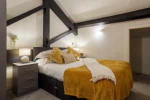 1 dormitorio con 1 cama grande con mantas y almohadas amarillas en 2 Bed New York Style Loft Apartment Free Parking, en Bradford