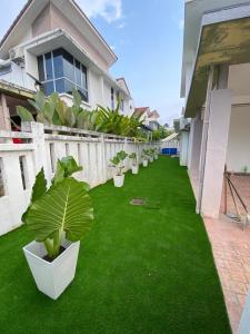 a yard with green grass and potted plants on it at Mysha KLIA F1 Homestay with pool,WiFi , Netflix in Kampong Chinchang
