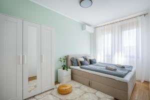 Prime Location Apartment في بودابست: غرفة نوم بيضاء بها سرير ونافذة