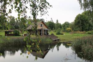 a house sitting next to a river with a house at Cabin with a sauna& pond+a hot Tub(additional fee) in Ķeņini
