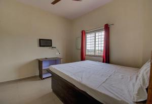 - une chambre avec un lit et une fenêtre avec des rideaux rouges dans l'établissement SPOT ON San Tower Hotel, à Kilimanūr